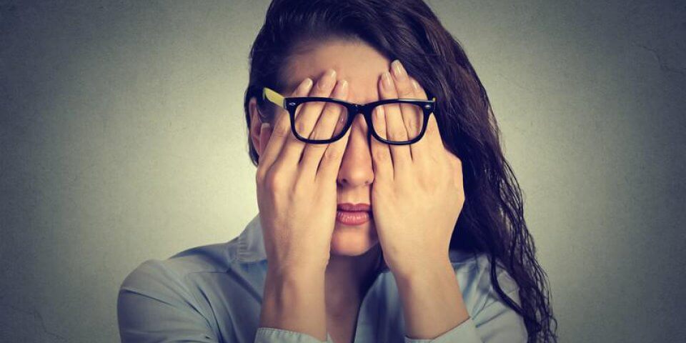 Jeune femme ayant les mains sur ses yeux signifiant un mal de tête