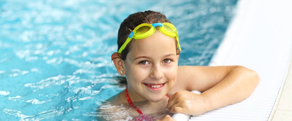 Cute girl with goggles in swimming pool