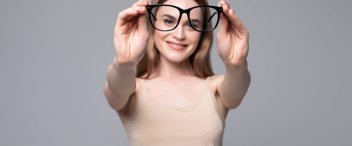 Glasses - optician showing eyewear. Closeup of glasses, with glasses and frame in focus. Woman optometrist on white background.